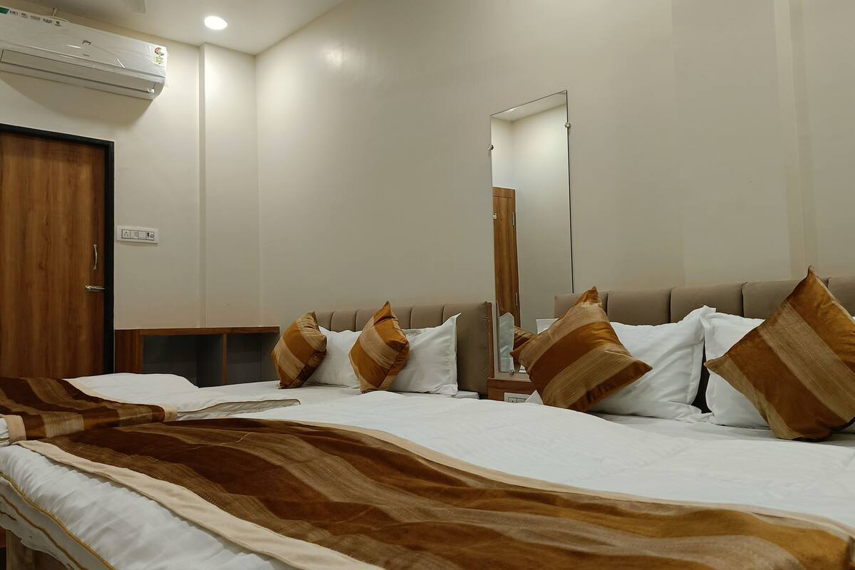 Une chambre d’hôtel avec un grand lit, une armoire en bois, un miroir et un appareil de climatisation.