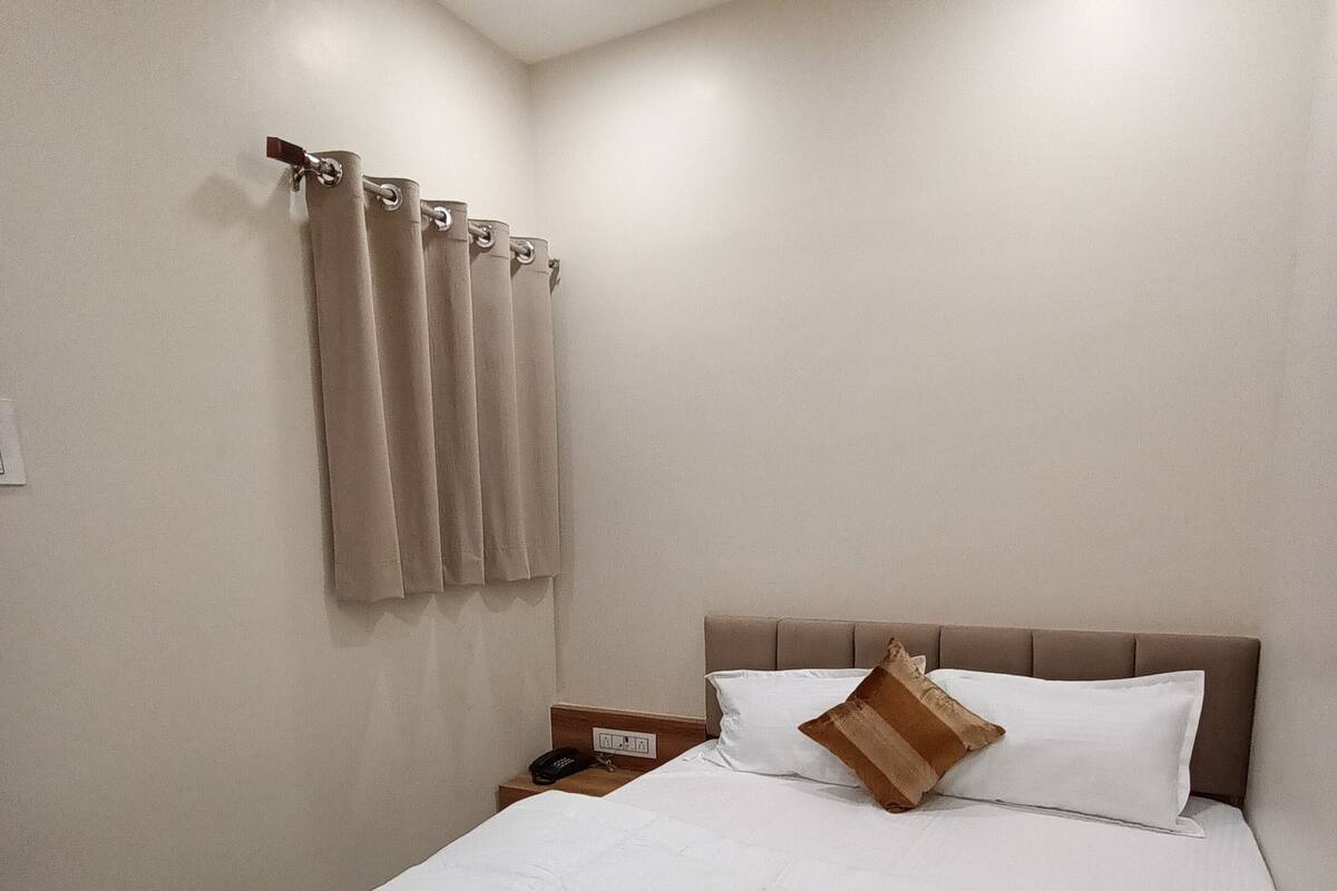 Un lit bien fait, avec une couverture à rayures, une table de chevet sur laquelle se trouve un téléphone et une tête de lit.