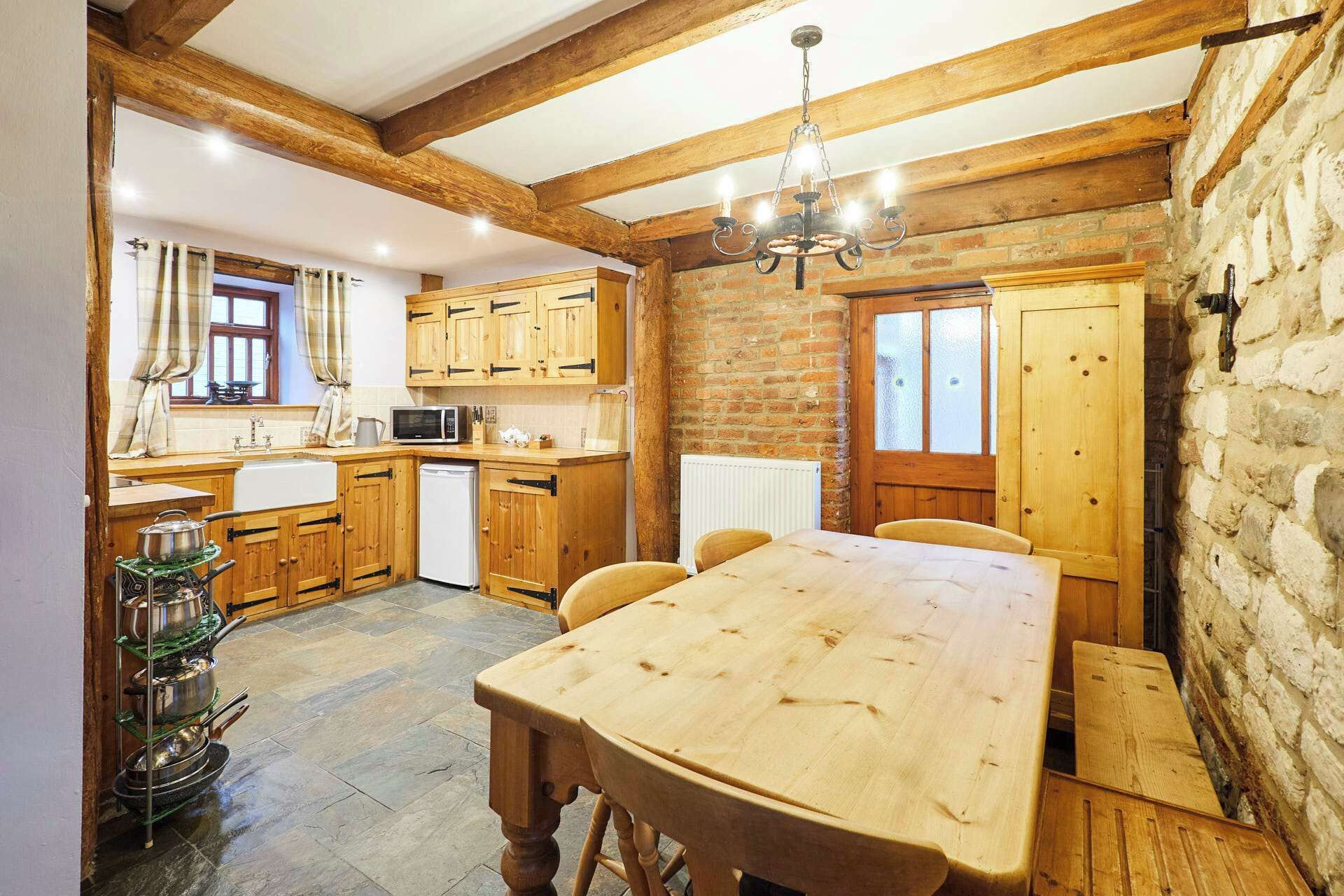 Une cuisine rustique avec des meubles de rangement en bois, un mur en pierre et une table à manger en bois.