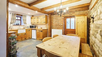 Une cuisine rustique avec des meubles de rangement en bois, un mur en pierre et une table à manger en bois.