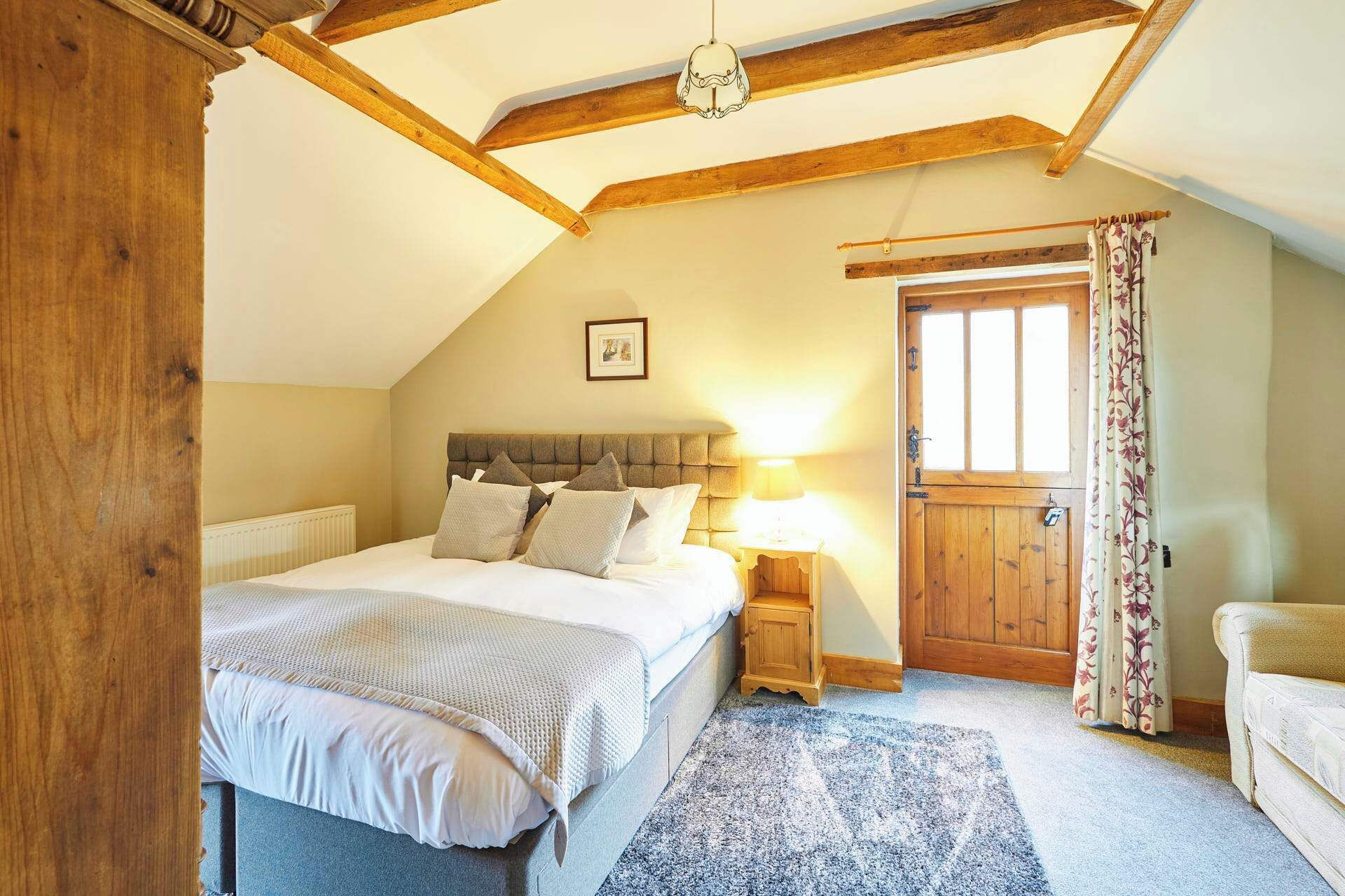A bedroom with a bed, a nightstand, a wooden door, and a window.
