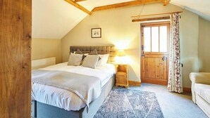 Een slaapkamer met een bed, nachtkastje, houten deur en raam.