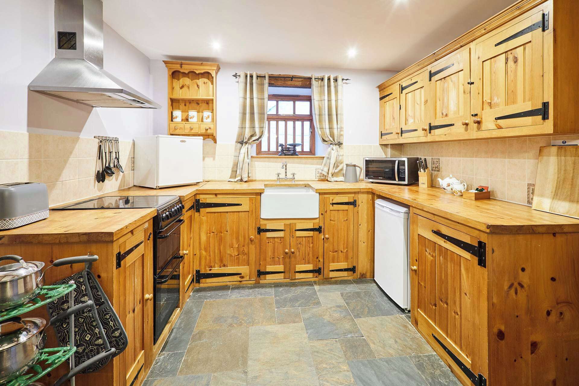 A kitchen with wooden cabinets, a stove, a microwave, and a sink.