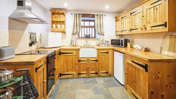 A kitchen with wooden cabinets, a stove, a microwave, and a sink.
