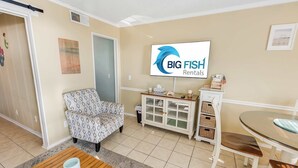 A living room with a sofa, a glass-top table, a cabinet with baskets, and a television displaying 'BIG FISH Rentals'. - North Myrtle Newly Remodeled Oceanfront View Suite (North Myrtle Beach)