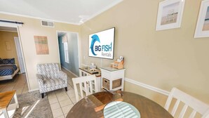 A furnished living room with a round wooden table, a patterned armchair, and a white cabinet. - North Myrtle Newly Remodeled Oceanfront View Suite (North Myrtle Beach)