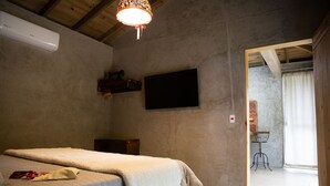 Un dormitorio con cama, televisor montado y ventilador de techo.