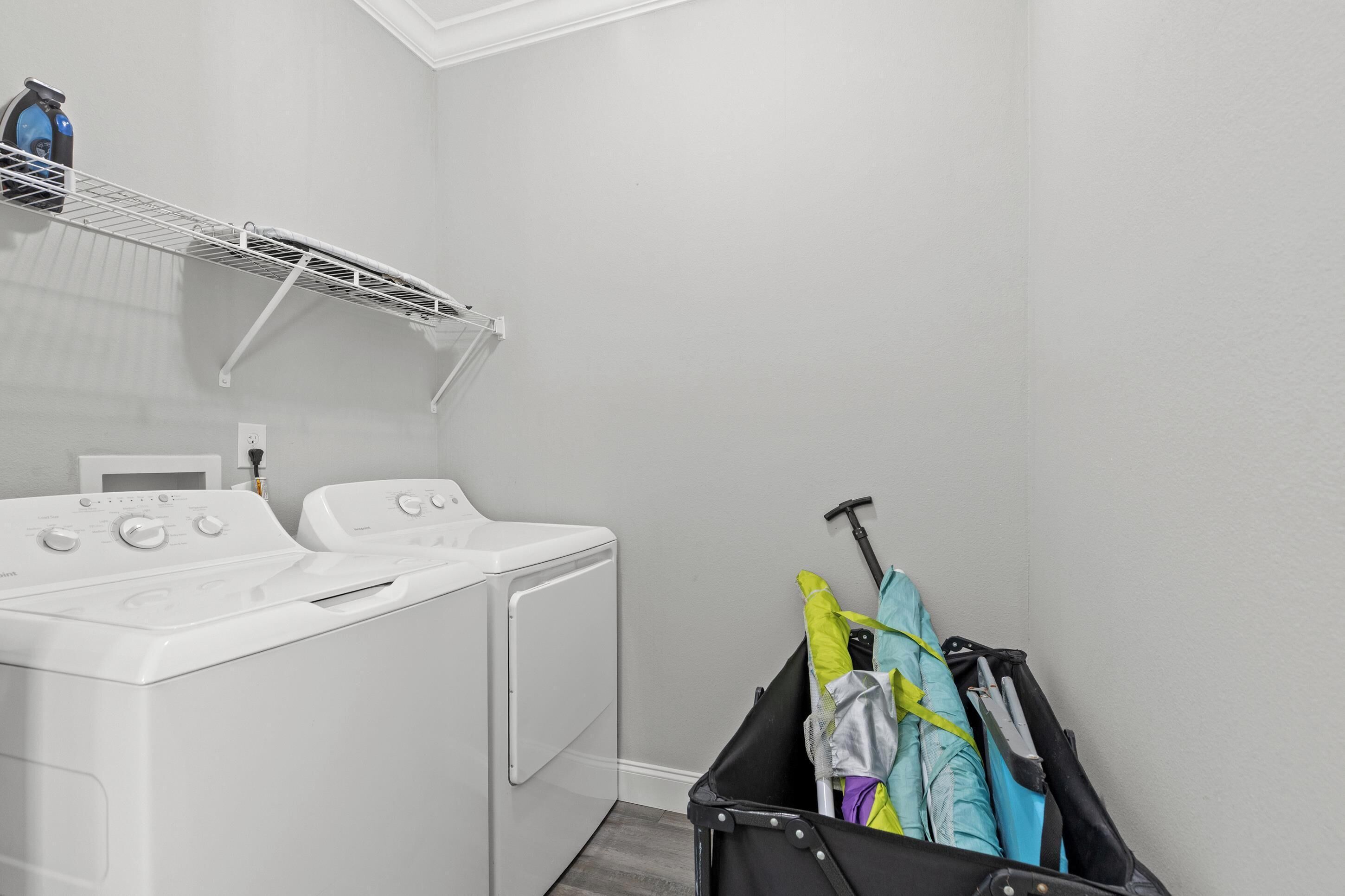 Een wasruimte met een wasmachine, droger en een droogrek.