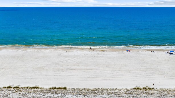 Una playa con cielo despejado y mar tranquilo.