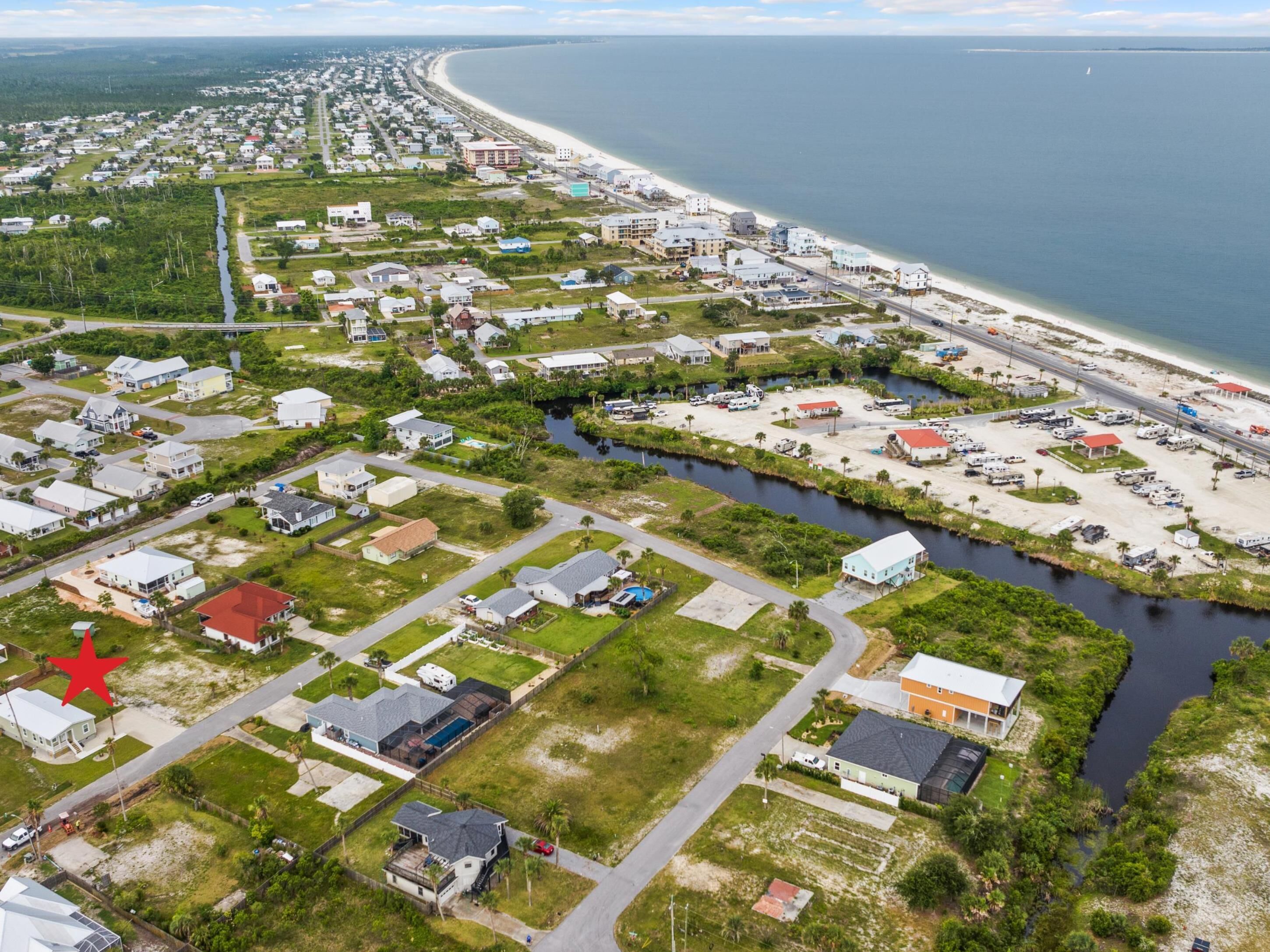 An aerial view of a coastal residential area with houses, a marina, and a beach.