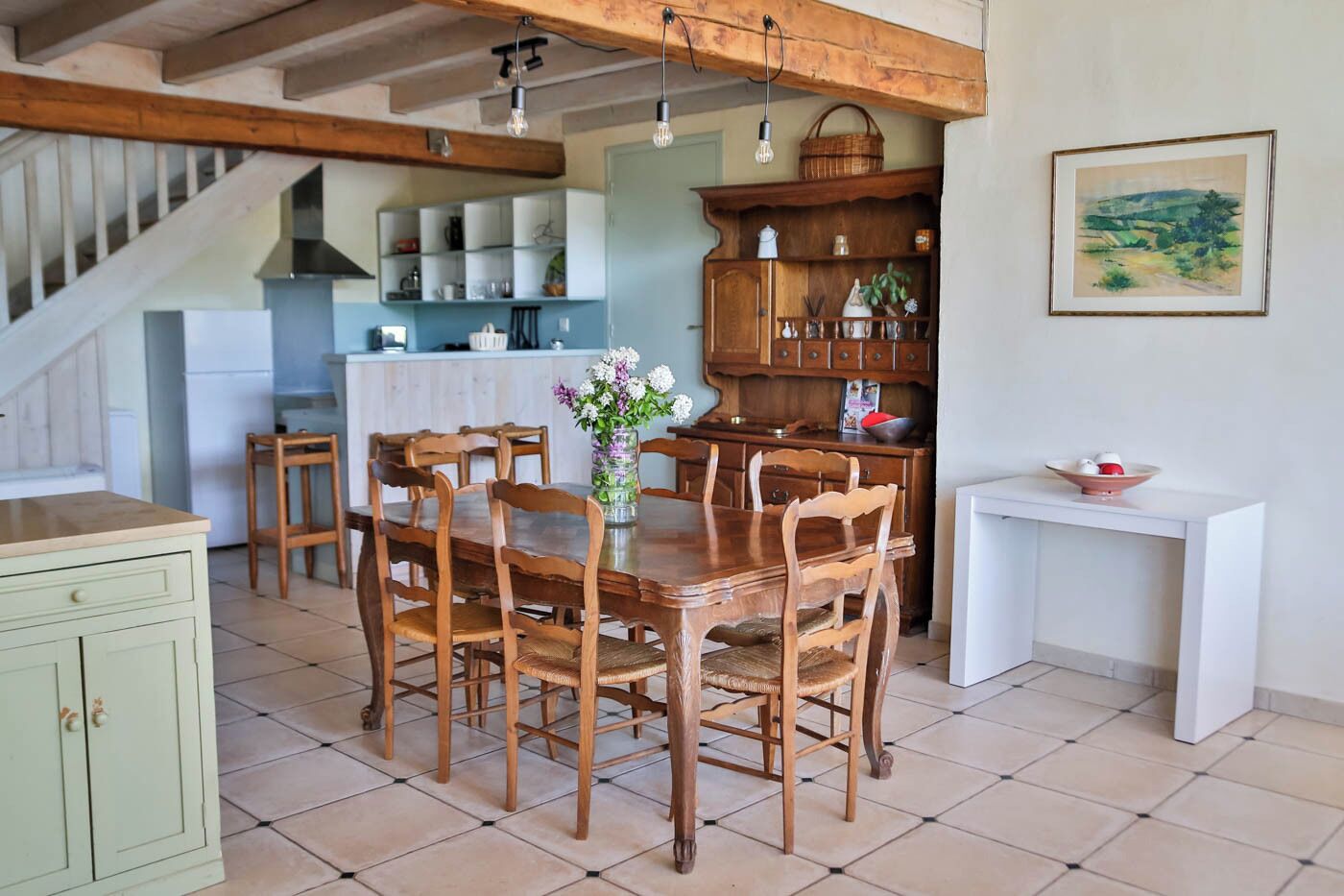 Une cuisine spacieuse avec des meubles de rangement en bois, une table à manger avec des chaises et un comptoir blanc.