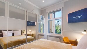 Une chambre d’hôtel avec un lit, une chaise, un bureau, un miroir et une grande fenêtre.