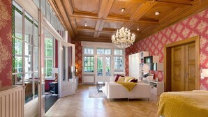 Une pièce spacieuse avec un grand lit, un lustre, un plafond en bois et de grandes fenêtres.