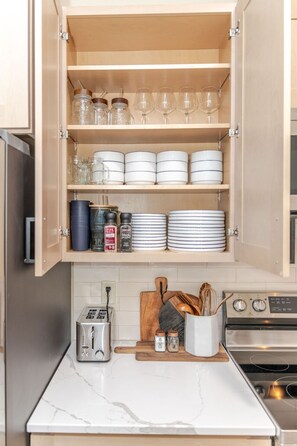 Una cocina con un armario de madera que contiene frascos de vidrio, platos y saleros.