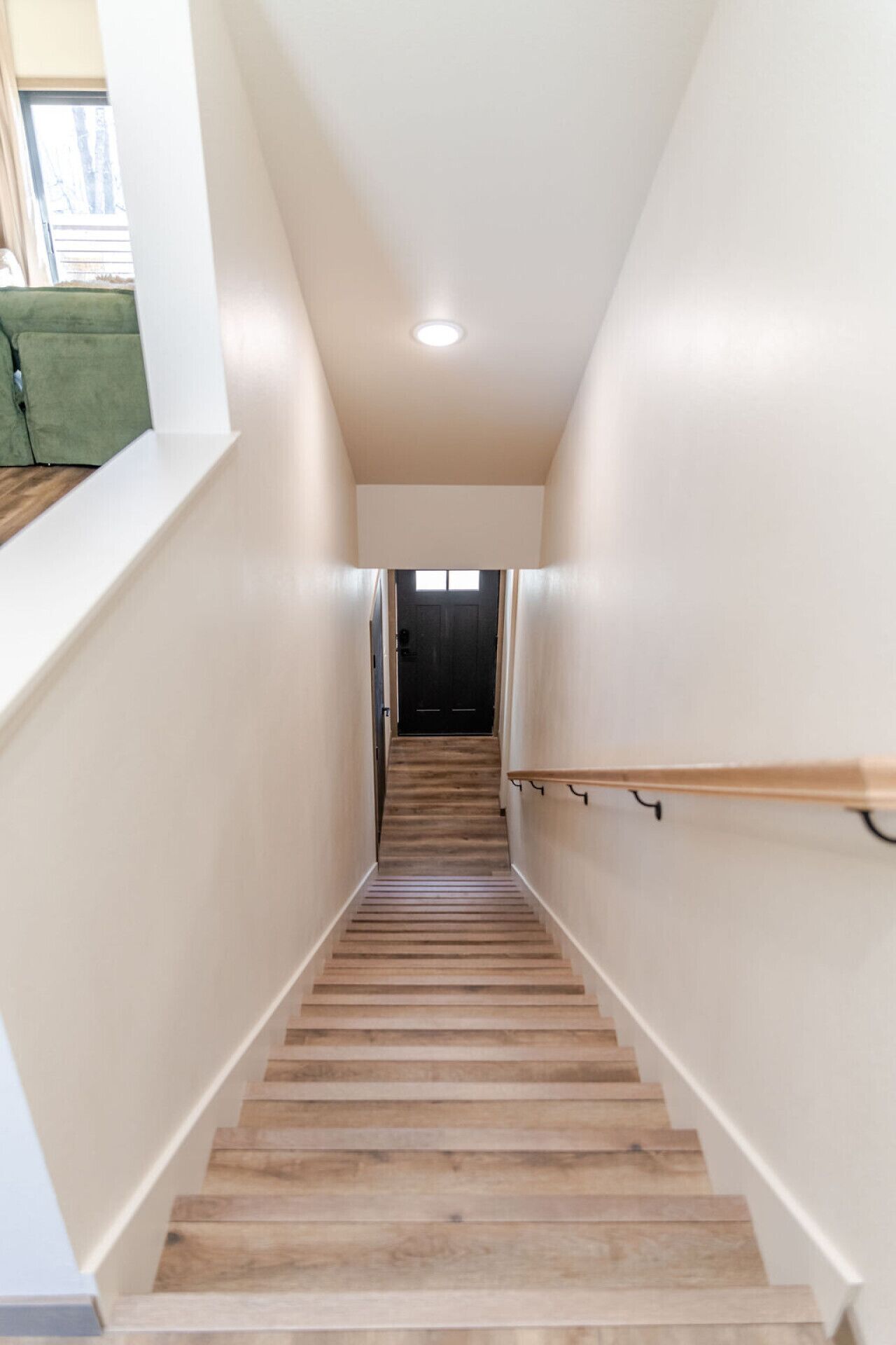 Un escalier avec des marches en bois et une rampe, menant à une porte sombre située en haut.