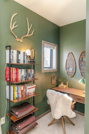 Una habitación con una estantería, un escritorio, una silla y una ventana.