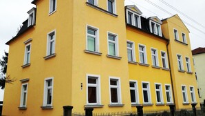Un edifici groc de diversos pisos amb nombroses finestres i una porta ben visible.