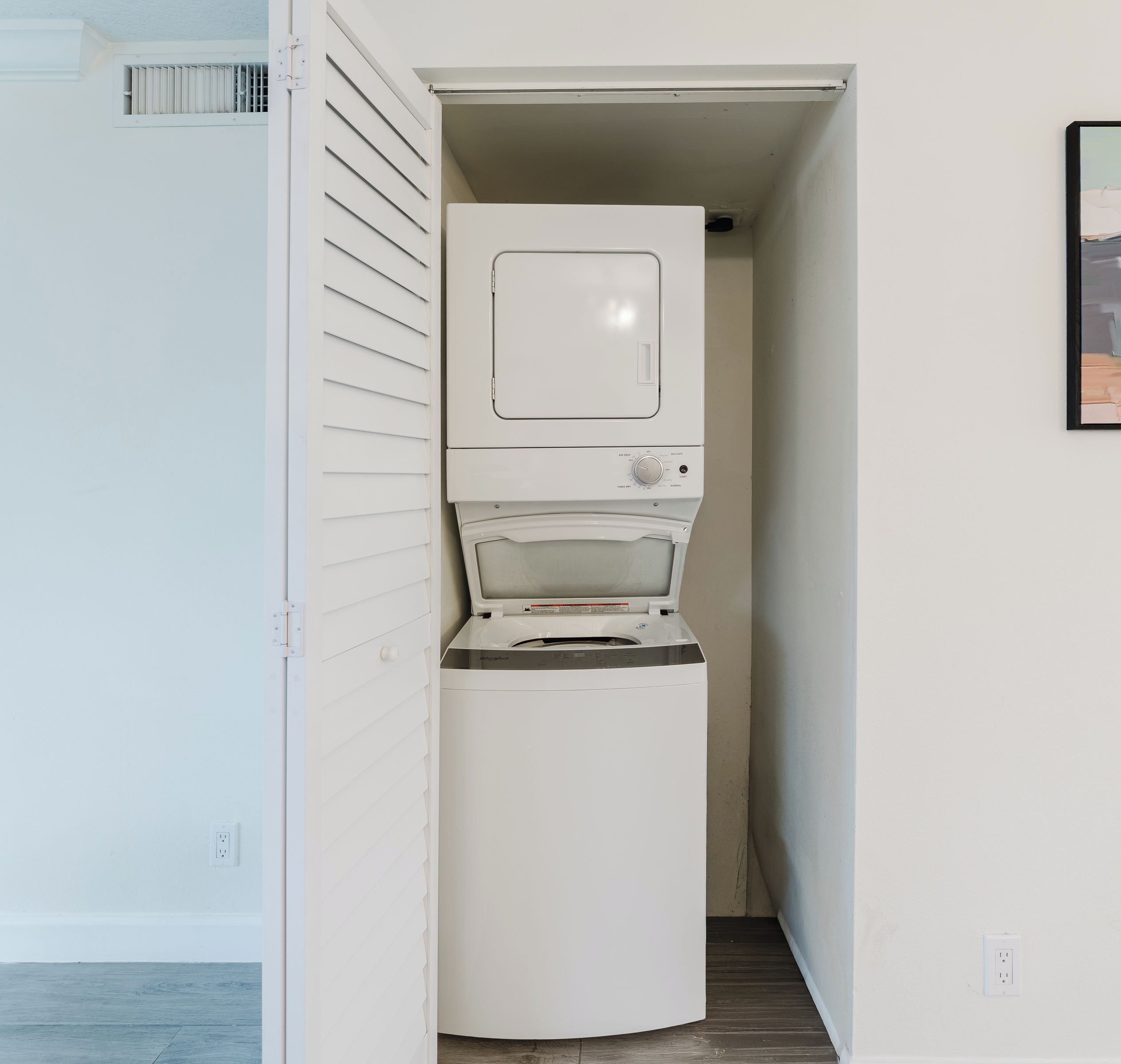 A laundry room with a washing machine and dryer stacked vertically.