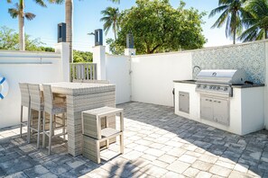 Un patio con una parrilla, mobiliario de mimbre y un revoque de azulejos.