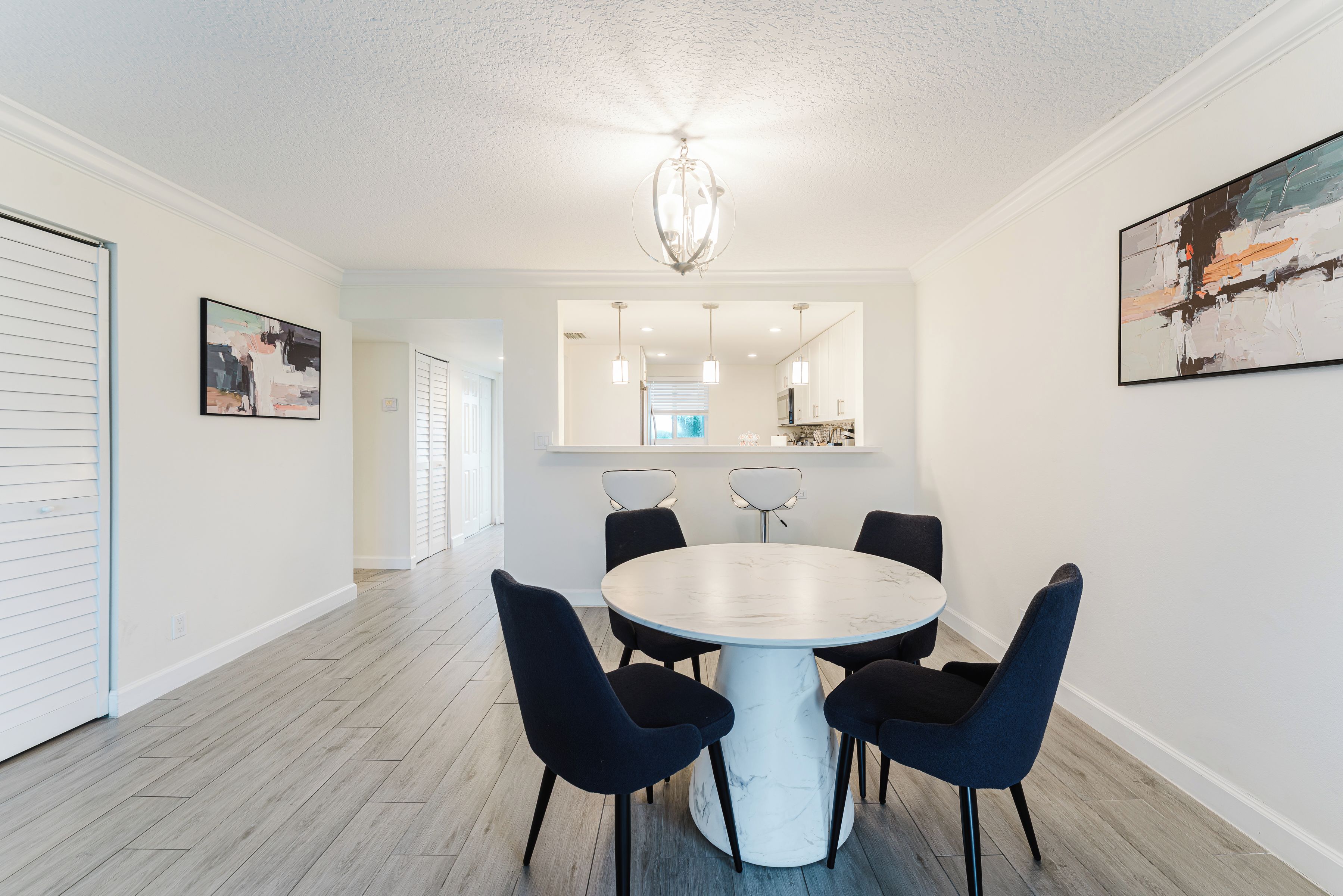 A modern dining area with a round table, six chairs, and a chandelier.