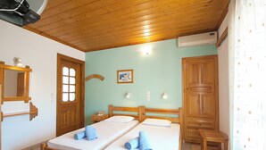 Une pièce comprenant deux lits en bois, une armoire en bois, une petite table en bois et un miroir.