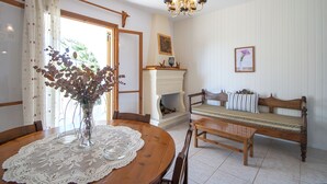 Un coin repas comprenant une table en bois, des chaises, un vase avec des fleurs, une cheminée et un banc.
