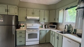 A kitchen with green cabinets, a refrigerator, an oven, a microwave, and a dishwasher. - Cornwall Cottage | Spacious, Fully Furnished Home for Corporate & Extended Stays (St. John's)