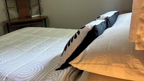 A neatly made bed with patterned bedding, a television on a wooden stand, and a plain wall. - Cornwall Cottage | Spacious, Fully Furnished Home for Corporate & Extended Stays (St. John's)