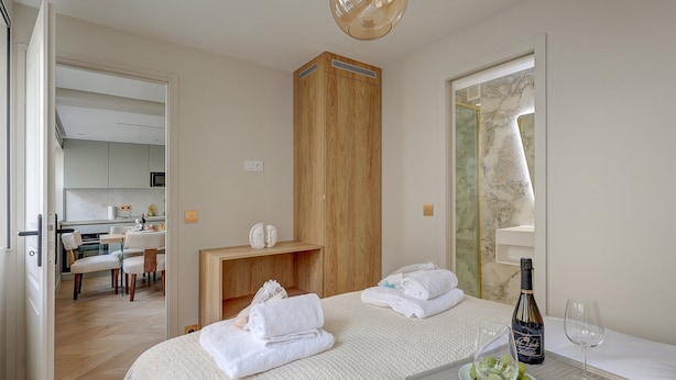 Ein Hotelzimmer mit Bett, einem Holzschrank, einer kleinen Küchenzeile und einem Badezimmer mit Marmorwand.