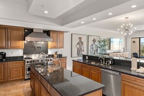 A modern kitchen with wooden cabinets, stainless steel appliances, and a large island. - 3 Bedroom • Sleeps 8 • Gulf-Front • Includes 1 Complimentary Beach Chair Set & 2 (Santa Rosa Beach)
