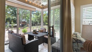 Un patio techado con mobiliario de mimbre, una mesa y un ventilador de techo.