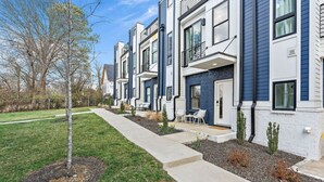 A row of modern townhouses with a well-maintained lawn, a paved walkway, and outdoor seating. - Lucky #7 Hip East Nash Townhome + Rooftop Deck (Nashville)