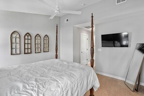 Ein Schlafzimmer mit Bett, Deckenventilator, Fernseher und Spiegel.