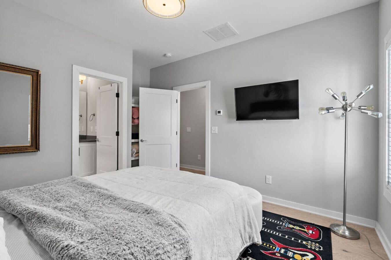 A bedroom with a bed, a TV, a coat rack, and a wardrobe.