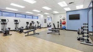 Une salle de sport équipée de divers appareils d’exercice, notamment des tapis de course, des vélos d’appartement et des appareils de musculation.