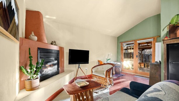 A cozy living room with a fireplace, a flat-screen TV, and comfortable seating. - Estrella De Oro Residences: Casita- Walk to town! (Golden)
