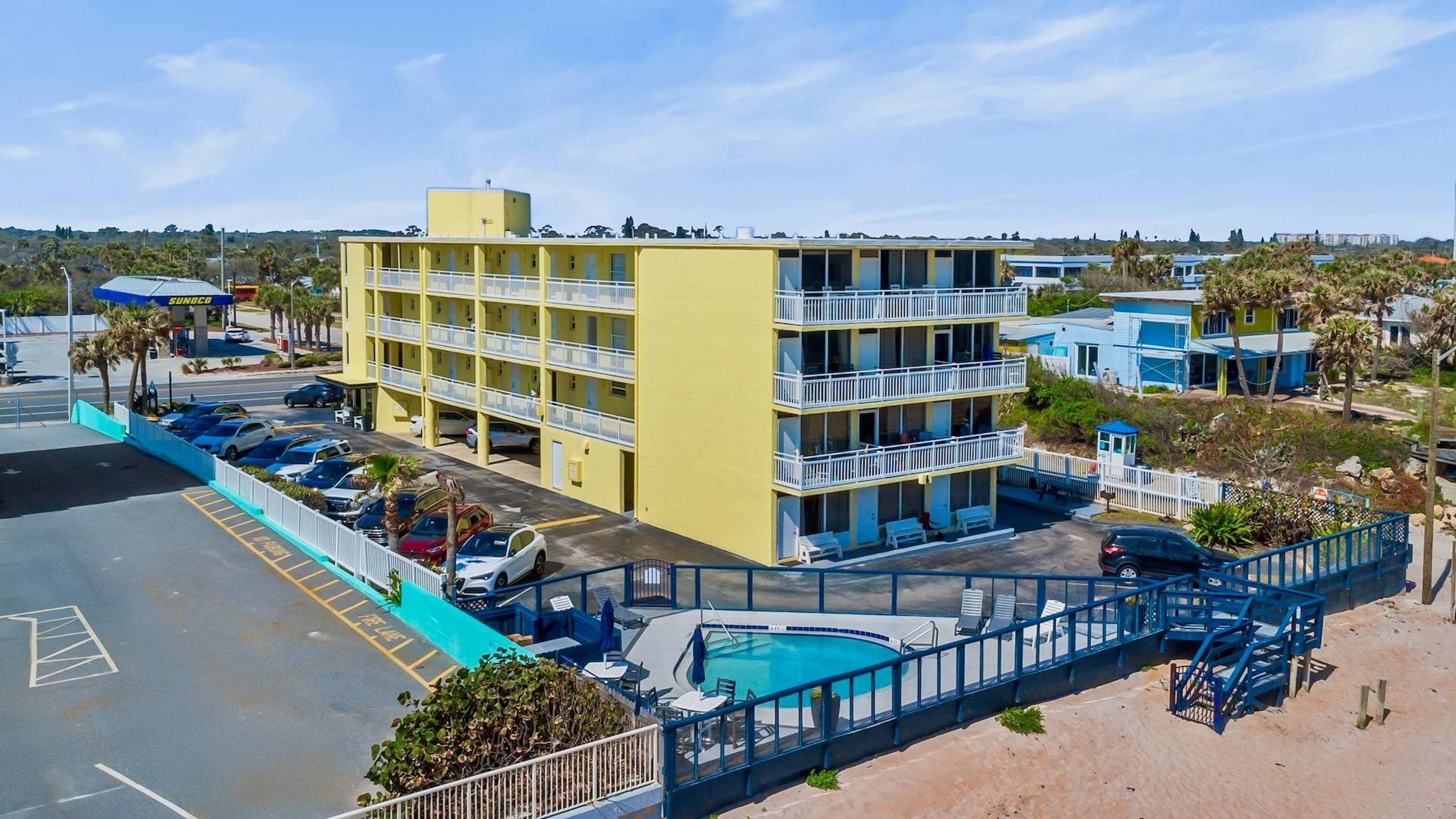 A multi-story hotel with a pool area, parking lot, and a visible gas station.