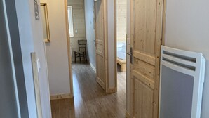 Un pasillo con piso de madera, una silla y una cama al fondo.