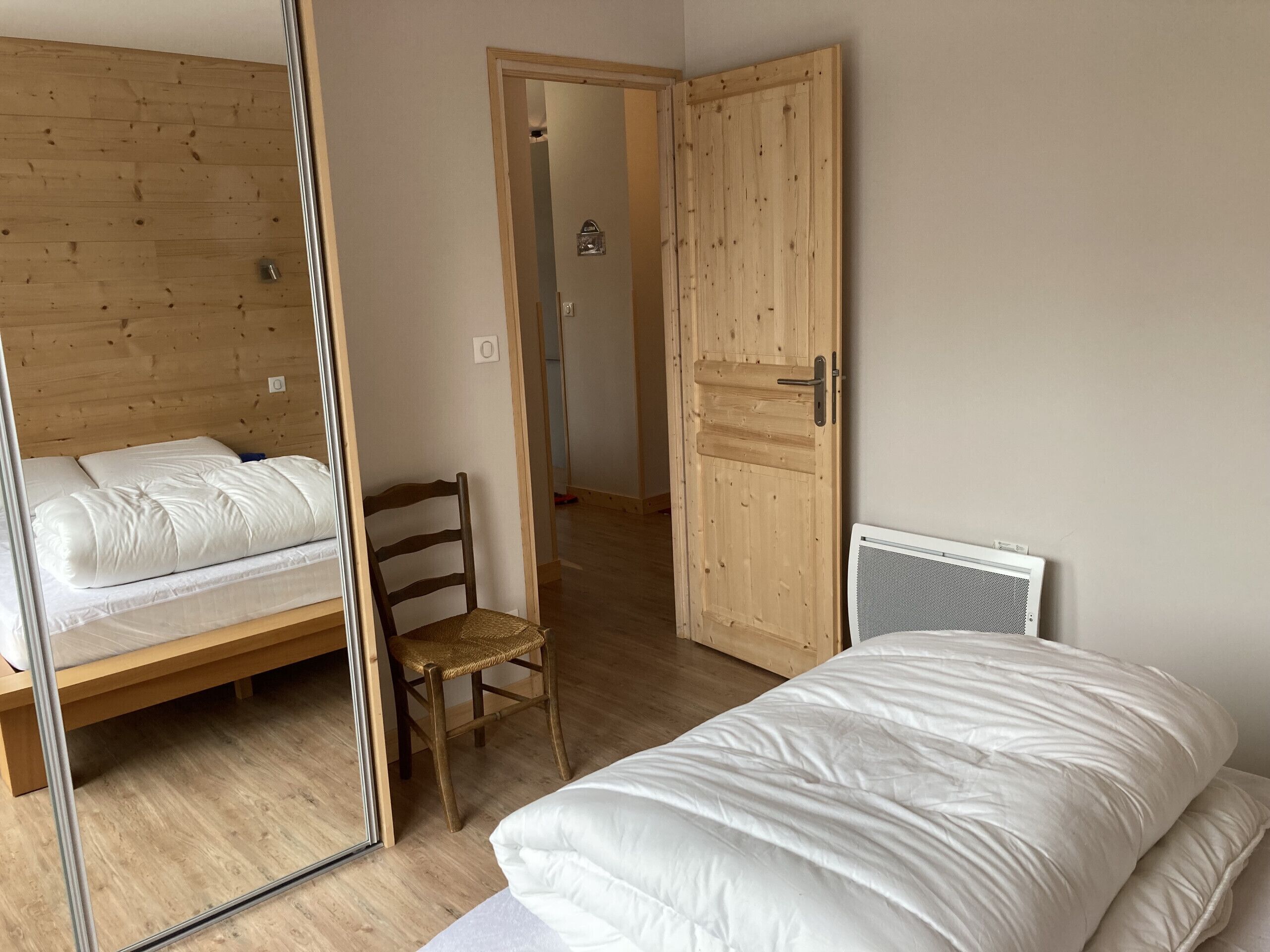 Een slaapkamer met een houten bed, een stoel en een kledingkast.