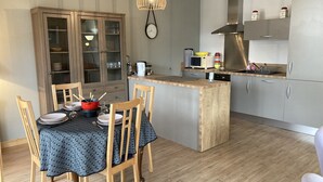 Una cocina compacta con una isla central, armarios de madera y un comedor con una mesa dispuesta para dos.