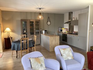 A compact kitchen with a dining area, featuring a wooden table, chairs, and a small island. - 2-bedroom chalet Aiguillon R-1G (Le Lioran)