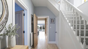 Ein Flur mit Holzboden, weißen Wänden und einer Treppe mit weißen Wangen.