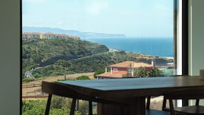 Vista desde una ventana a un paisaje costero con edificios y una carretera.