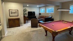 A living room with a pool table, a television, a sofa, and a piano. - Two Bedroom Basement Suite (Calgary)