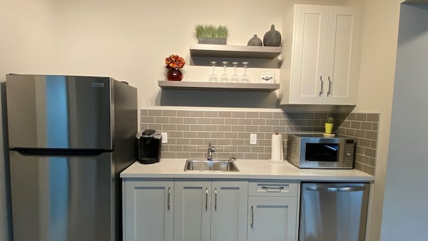 A modern kitchen with a stainless steel refrigerator, a microwave, and a sink. - Two Bedroom Basement Suite (Calgary)