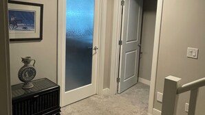 A hallway with a radiator, a framed picture, and a door with frosted glass. - Two Bedroom Basement Suite (Calgary)