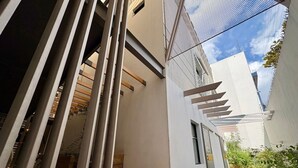 A narrow outdoor corridor with a tiled floor, a white wall, and a metal mesh structure. - DOUBLE SUITE - S4 (Heroica Puebla de Zaragoza)