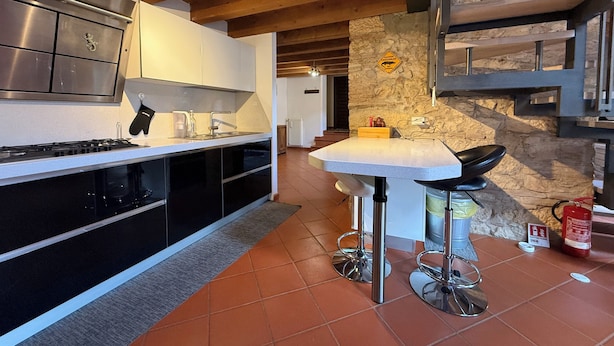 A modern kitchen with a central island, bar stools, and a stone accent wall. - Apartment in renovated rustic courtyard (Colognola Ai Colli)