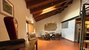 A dining area with a wooden table and chairs, a stone wall, and a tiled floor. - Apartment in renovated rustic courtyard (Colognola Ai Colli)