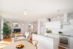 Ein modernes Wohnzimmer mit Fernseher, Sofa und Essbereich.
